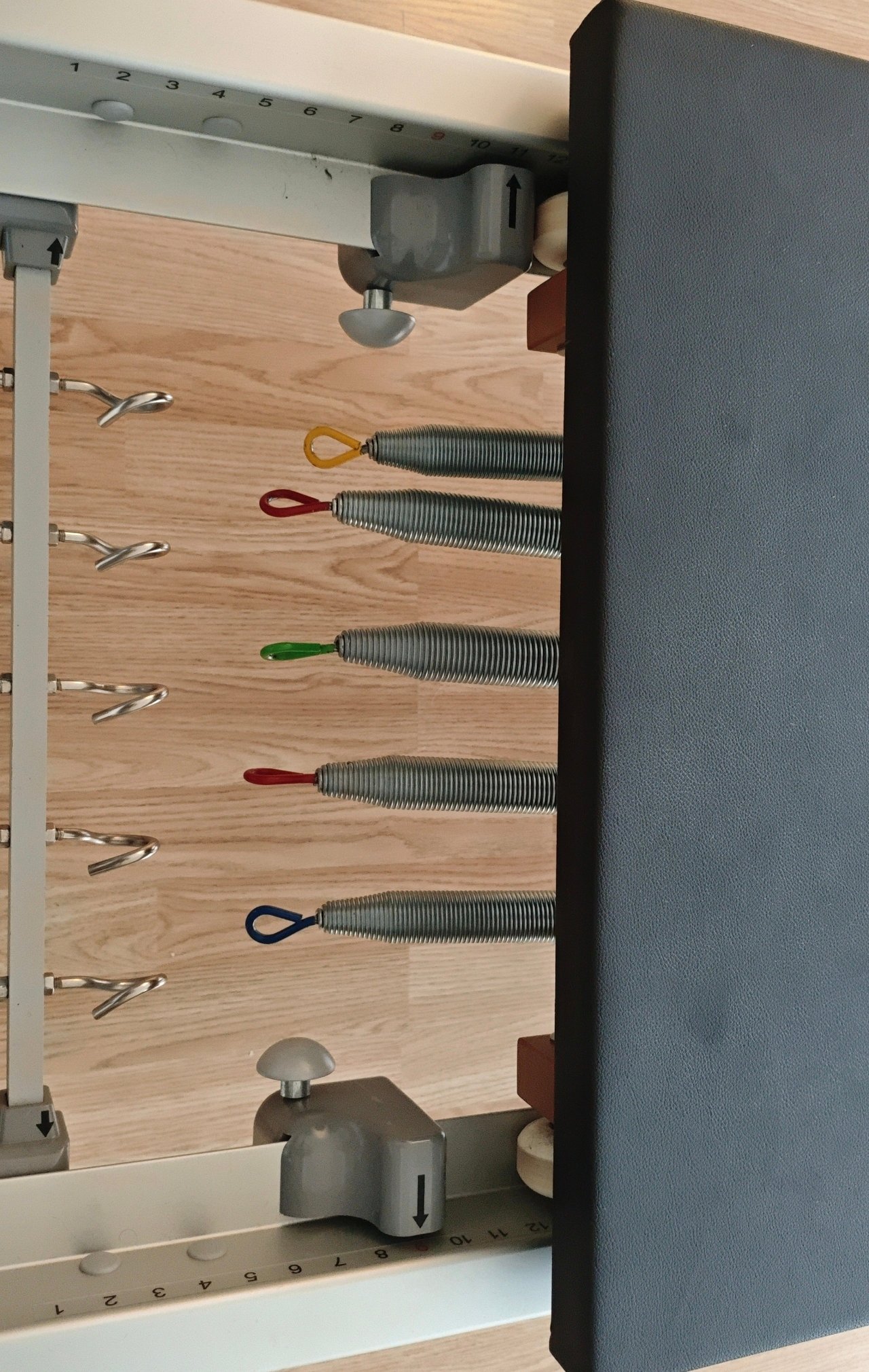 Close-up of the color-coded resistance springs on a Bonpilates Monitor Reformer and tower